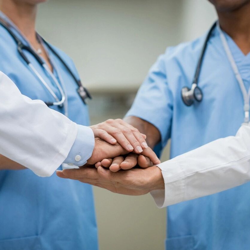 Two doctors holding hands with each other in a circle.